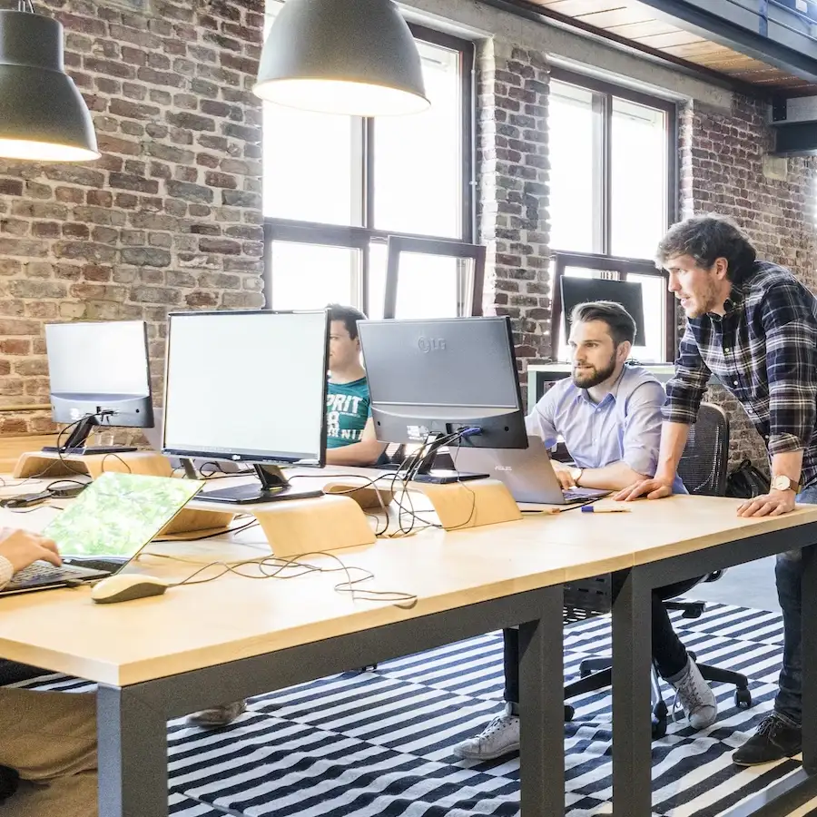 People working with computer monitors. People are show talking to one another. 